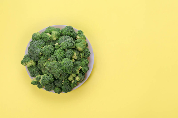 Fresh green broccoli on plate on yellow background. Top view. - Fotografie, Obrázek
