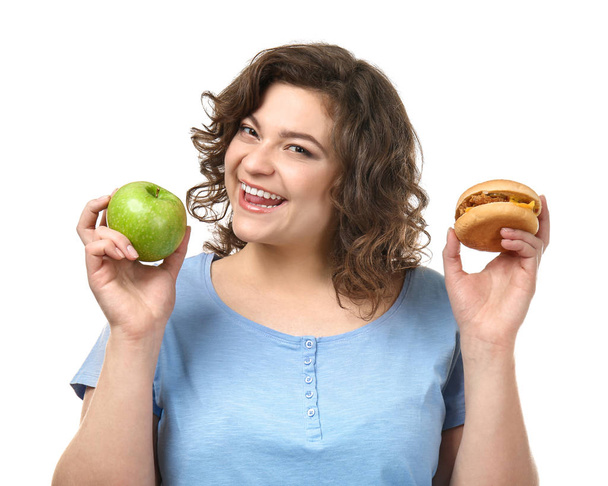 Túlsúlyos nő, alma és hamburger fehér háttérrel. Az egészséges és egészségtelen ételek közötti választás fogalma - Fotó, kép