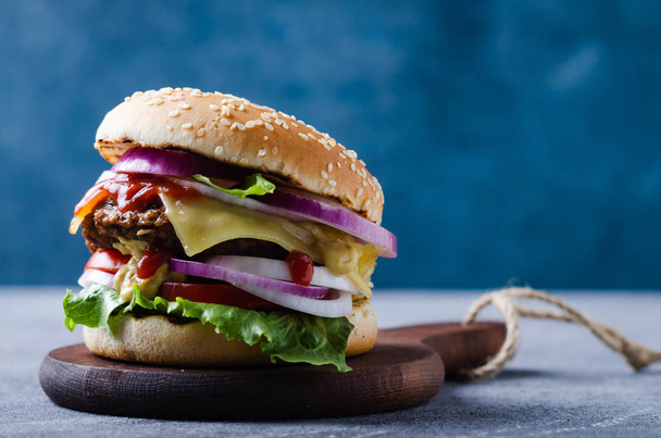 Tradiční burgery s kotlet, čerstvá zelenina, křupavý houska se sezamovou semínkou na šedém dřevěném stole. - Fotografie, Obrázek