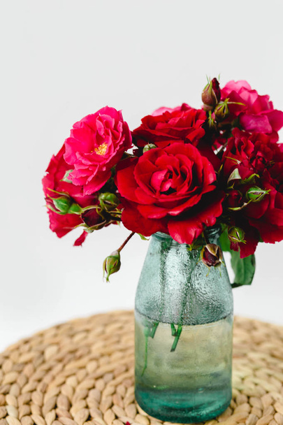 Superbe composition de roses colorées dans un vase sur une serviette en osier
 - Photo, image