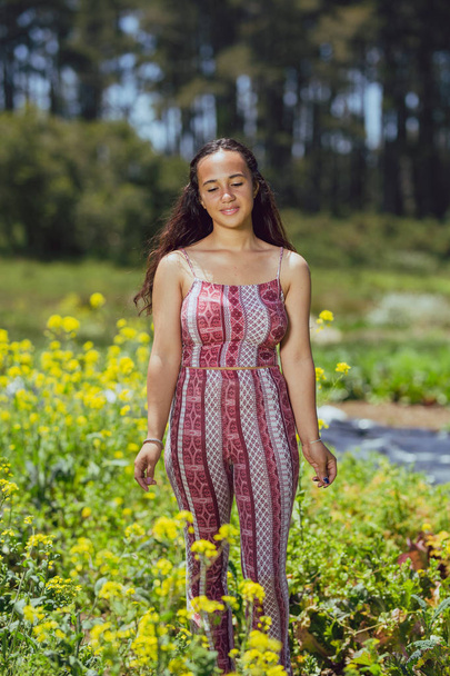 Mujer joven de raza mixta se encuentra en un campo de flores en una granja
 - Foto, imagen