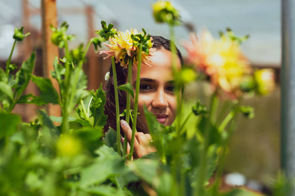 Mixed race young woman stands in a flower greenhouse on a farm - Photo, Image