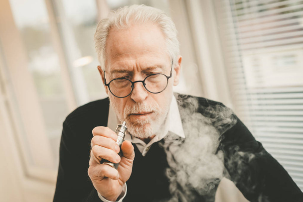 Senior man smoking electronic cigarette - Фото, зображення