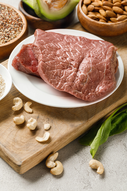 fındık ile ahşap doğrama tahtası üzerinde çiğ et, ketojenik diyet menüsü - Fotoğraf, Görsel