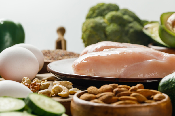 灰色のケト原性ダイエットメニューに分離された生の鶏の胸肉と卵の選択的な焦点 - 写真・画像