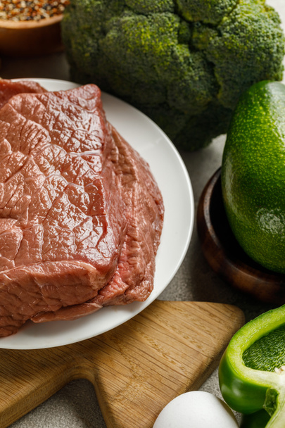 Close-up uitzicht op rauw vlees in de buurt van ei en avocado,, ketogeen dieetmenu - Foto, afbeelding