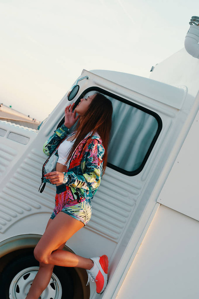 Young and carefree. Attractive young woman looking in the mirror and adjusting her lips while standing against food truck outdoors - Foto, immagini