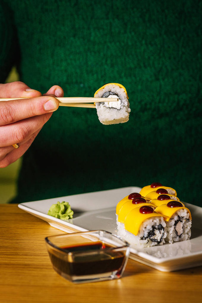 Männerhände halten Sushi mit Essstäbchen   - Foto, Bild