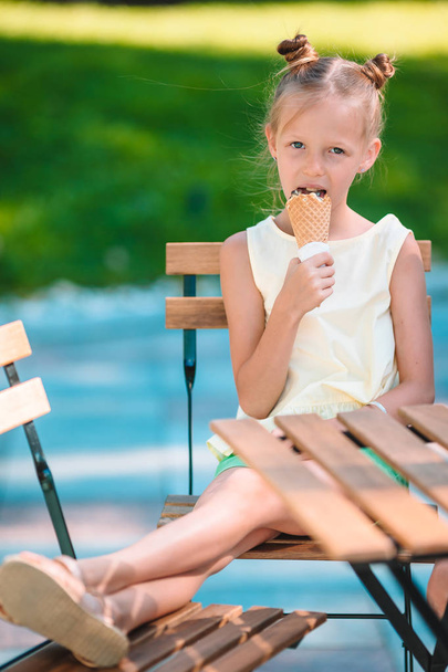 Little girl eating ice-cream outdoors at summer in outdoor cafe - Foto, Imagem