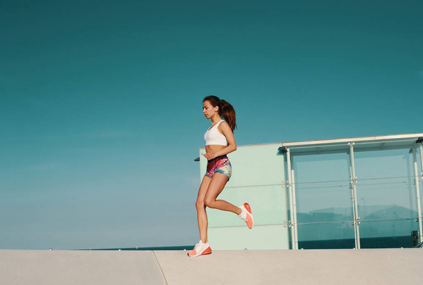 Longitud completa de la hermosa mujer joven en ropa deportiva trotando mientras hace ejercicio al aire libre
 - Foto, imagen
