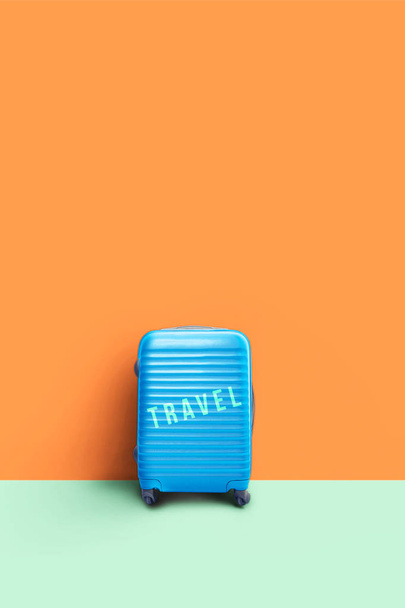 βαλίτσα τυρκουάζ στο χρώμα τοίχου με το μήνυμα "ταξίδια". Holi - Φωτογραφία, εικόνα