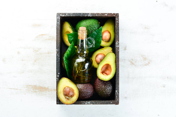 Avocado and avocado oil on a white wooden background. Rustic style. Top view. Free space for your text. - Foto, immagini