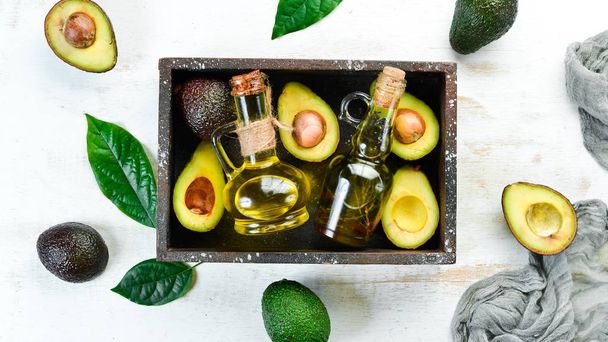 Avocado and avocado oil on a white wooden background. Rustic style. Top view. Free space for your text. - Φωτογραφία, εικόνα
