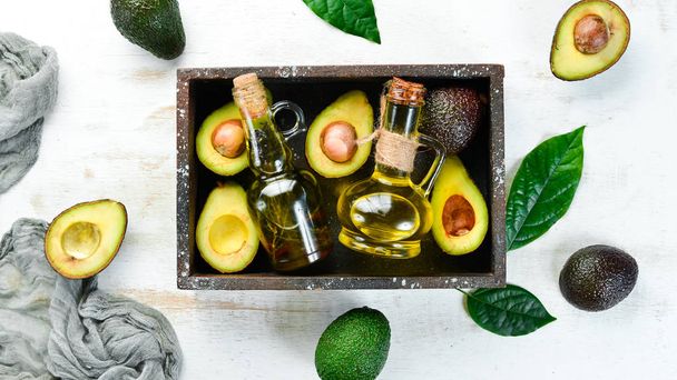 Avocado and avocado oil on a white wooden background. Rustic style. Top view. Free space for your text. - Photo, Image