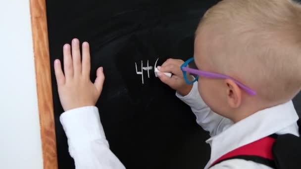 Cute little boy writing on blackboard. Child from elementary school with bag. Education concept. Back to school. - Metraje, vídeo