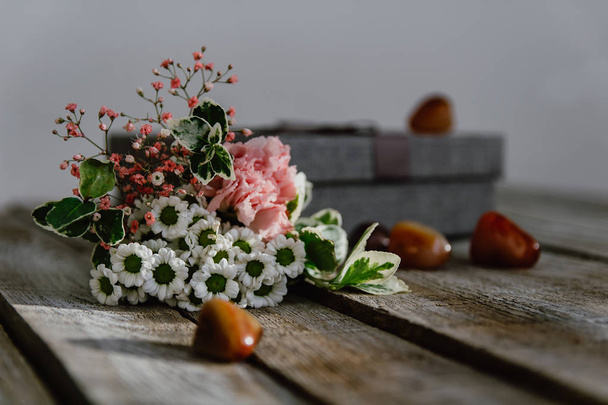 Μπουκέτο λουλουδιών με κουτί δώρου και πέτρα σε φόντο ξύλου. Η δυνατότητα b - Φωτογραφία, εικόνα