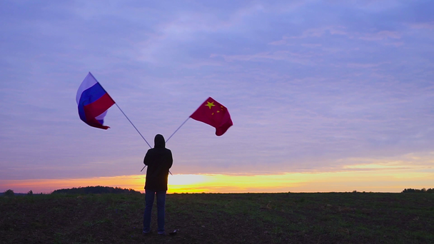 Μήκος σε πόδηα από ρωσικές και κινεζικές σημαίες πνέει στον άνεμο. κυματίζοντας σημαιών μέσα σε ένα τοπίο. Σημαία Ρωσίας Κίνα. - Πλάνα, βίντεο