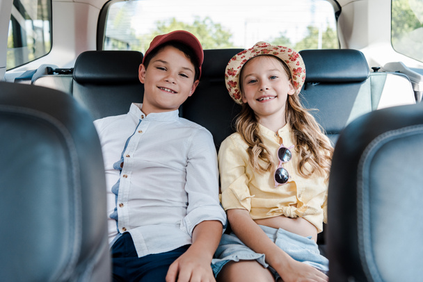 selective focus of happy sister and brother smiling while sitting in car  - Fotoğraf, Görsel