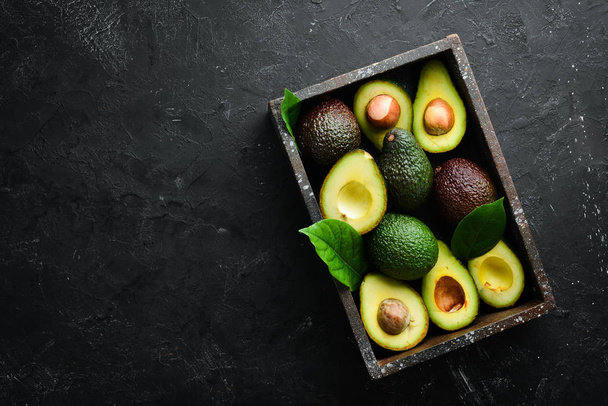 Avocado with leaves in the box. Rustic style. Top view. Free space for your text. - Foto, Bild