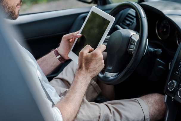 cropped view of man sitting in car and using digital tablet  - Fotó, kép