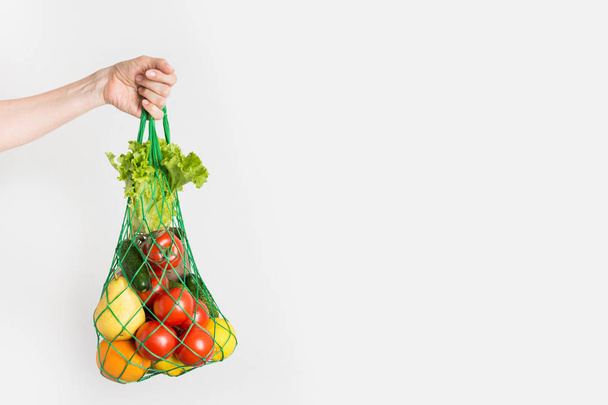 Mesh bag of fruits, vegetables, greens in woman's hand. Zero waste. Plastic free. - Photo, Image