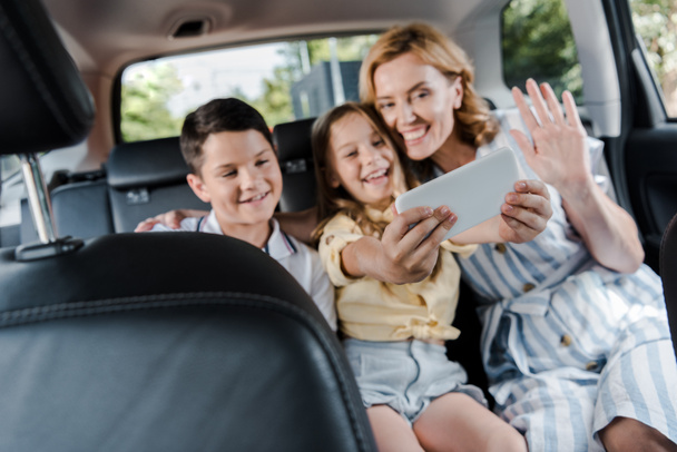 foyer sélectif de la famille heureuse prendre selfie sur smartphone dans la voiture
  - Photo, image