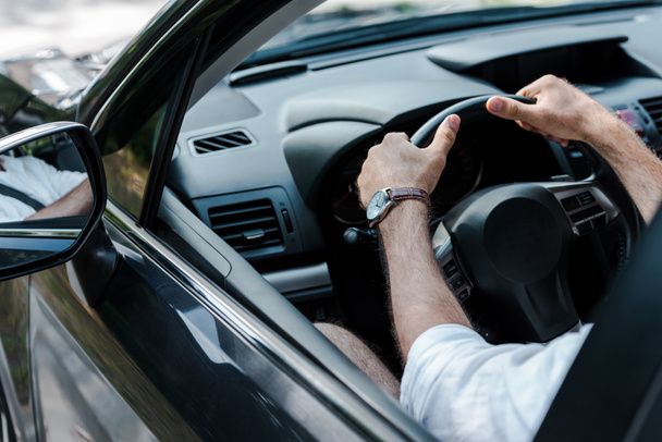 wykadrowany widok mężczyzny trzymania kierownicy podczas jazdy samochodem  - Zdjęcie, obraz