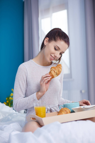 Attractive woman eating cereals sitting on bed at home - Φωτογραφία, εικόνα