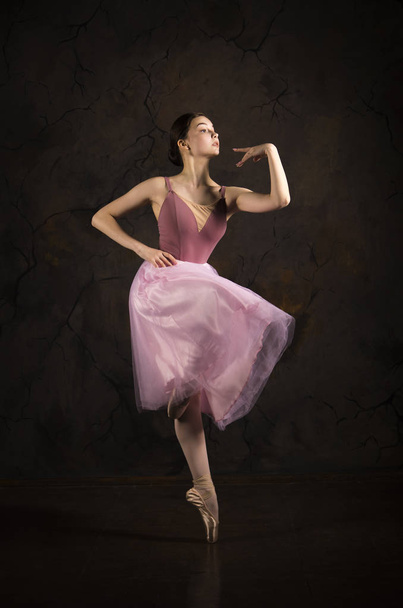 A slender girl in a pink skirt and beige top dancing ballet. - Foto, imagen