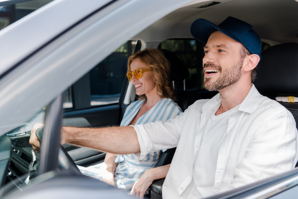 selective focus of happy man driving car near attractive woman in sunglasses  - Zdjęcie, obraz