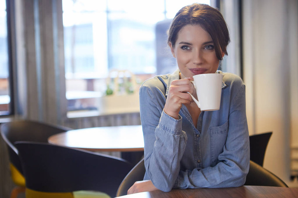 A young woman having coffee in office - Фото, зображення