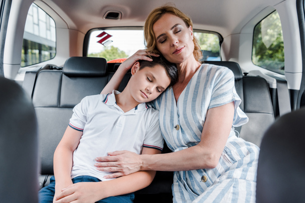selective focus of mother and son with closed eyes in car  - Fotoğraf, Görsel
