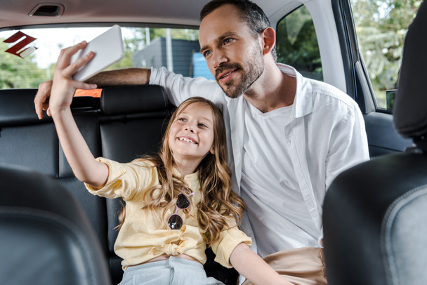 foyer sélectif de gosse heureux parlant selfie avec père en voiture
  - Photo, image
