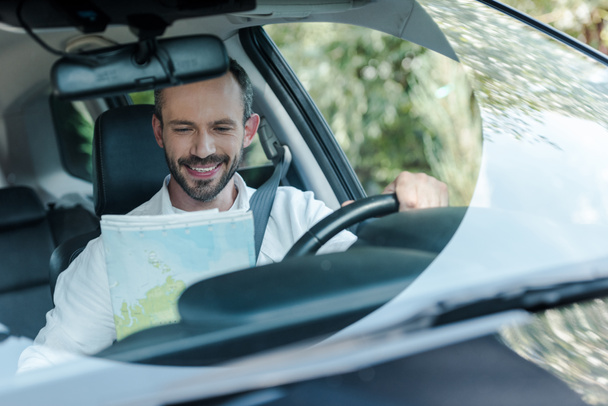 車を運転し、地図を見て幸せな男の選択的な焦点  - 写真・画像