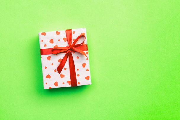 Caja de regalo con cinta roja y corazón sobre fondo verde, vista superior con espacio de copia para texto
 - Foto, imagen