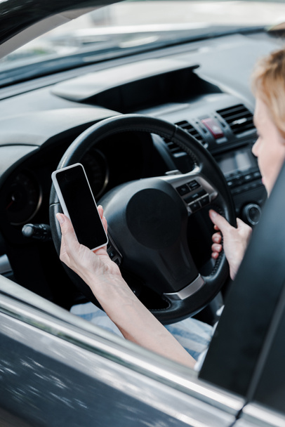 cropped view of woman holding smartphone with blank screen in automobile - Фото, изображение