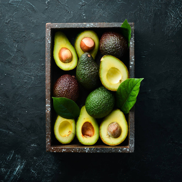 Avocado with leaves in the box. Rustic style. Top view. Free space for your text. - 写真・画像