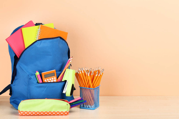 Backpack with school supplies on beige background - Фото, изображение