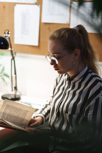 Photo of blonde european woman architect wearing glasses designing draft and sitting at workplace - Valokuva, kuva