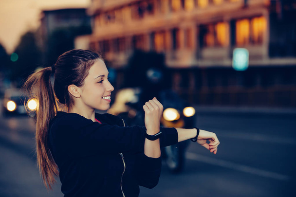 Νέα γυναίκα κάνει τέντωμα άσκηση στην πόλη, το βράδυ - Φωτογραφία, εικόνα