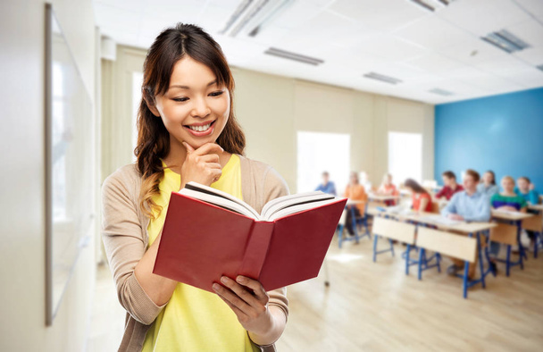 happy asian woman reading book at school - 写真・画像