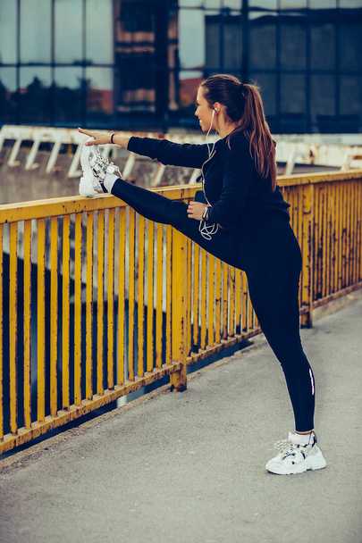 junge Frau streckt ihre Beine auf Flussbrücke aus - Foto, Bild