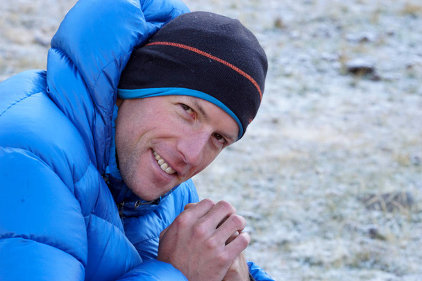 close up of a male mountain climber in a thick down jacket looki - Photo, Image