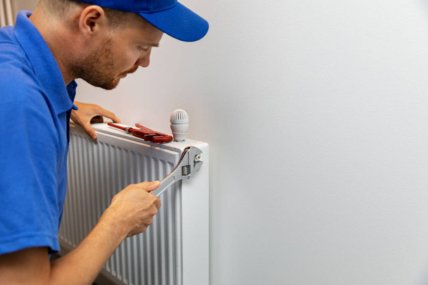 ラジエーターを設置するハウス暖房システム設置配管工 - 写真・画像
