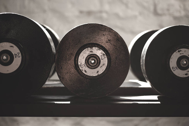 Black steel dumbbell set. Close up of dumbbells on rack in sport fitness center. Workout training and fitness gym concept. - Photo, Image