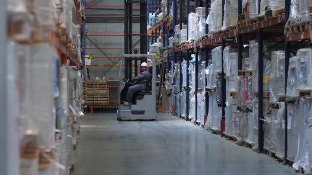 Een vorkheftruck rijdt langs enorme stands met goederen in een logistiek magazijn. 4k slow mo - Video