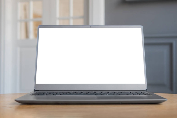 Сірий ноутбук з білим порожнім екраном на дерев'яному столі в інтер'єрі
 - Фото, зображення