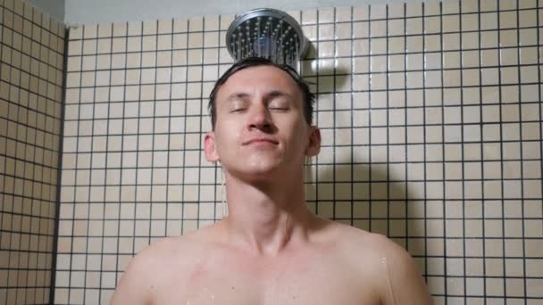 Portrait of young man is taking a shower combing his hairs with hands. - Video