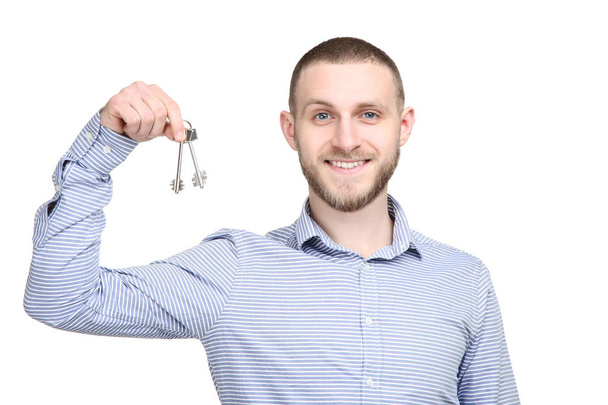 Young man holding silver keys on white background - Foto, imagen