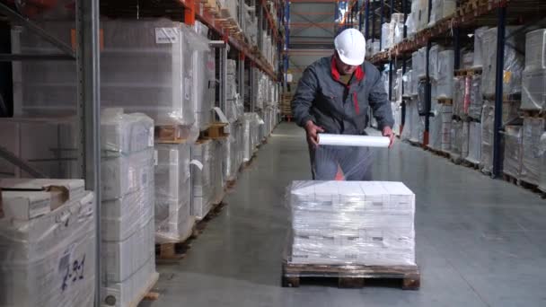 Logistiklager. Der Arbeiter packt Paletten mit Produkten. 4k langsam mo - Filmmaterial, Video